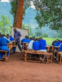 Teacher instructing students seated at outdoor desks