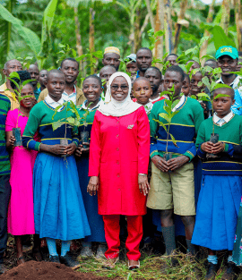Students and community leaders holding tree saplings at Rushe Primary School