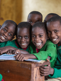 Group of smiling primary school students gathered at a desk