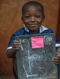 Smiling young boy holding up a small chalkboard